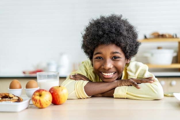 Close up smiling little boy drink glass of milk sitting at wood