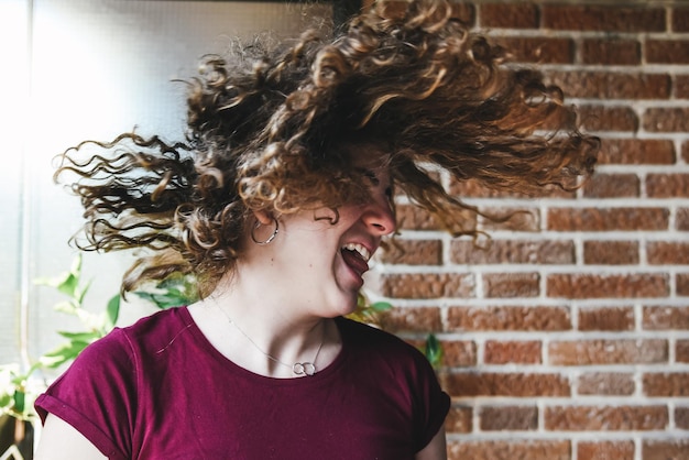 Photo close-up of smiling young woman tousled hair against wall