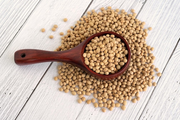 Close up of soybeans on a wood scope white table background flat lay