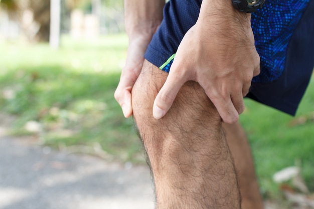 Close up of Sport man suffering with pain on sports running knee injury after running.Injury from workout concept.