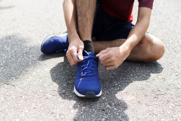 Close-up of sportsman. He tying sneakers on running shoes before practice.