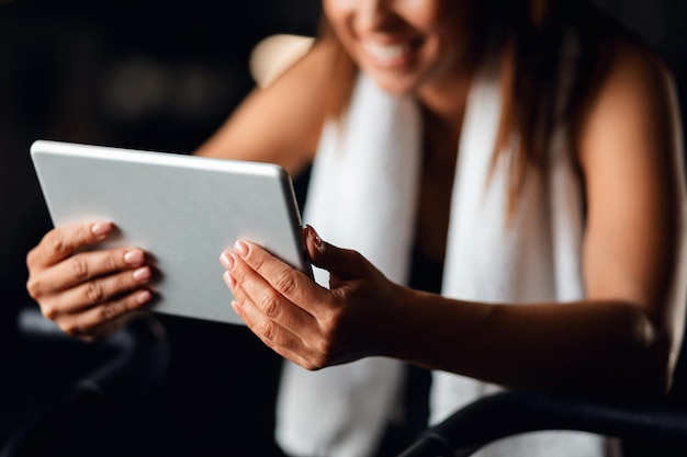 Close up of sportswoman using digital tablet while working out in fitness center