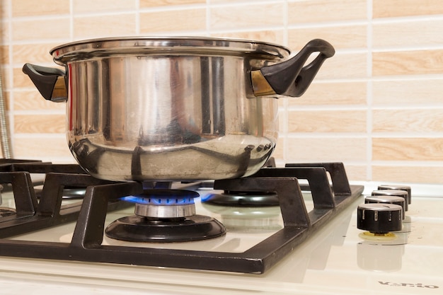 Close-up of stainless steel cooking pot on gas stove in contemporary upscale modern  home kitchen. Selective focus on pot.