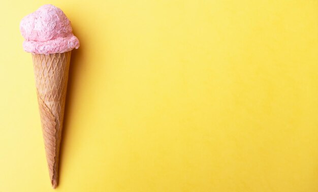 Close up strawberry ice cream in waffles cone against yellow background copy space