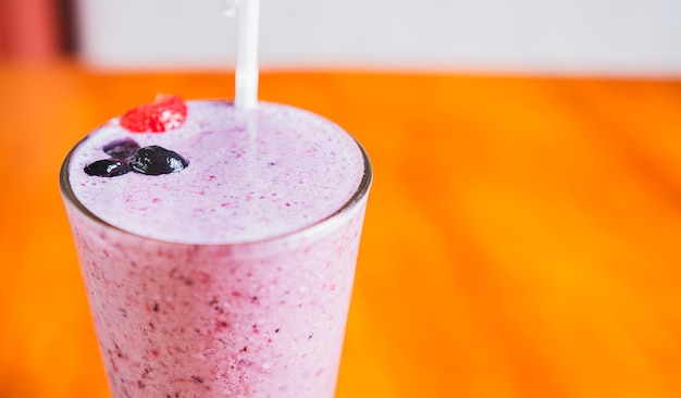 Close up of a strawberry milkshake in blurred background with copy space Strawberry smoothie with blueberry on wooden background