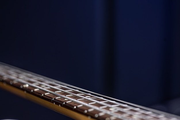 Close up of strings on bass guitar on blurred black background copy space.