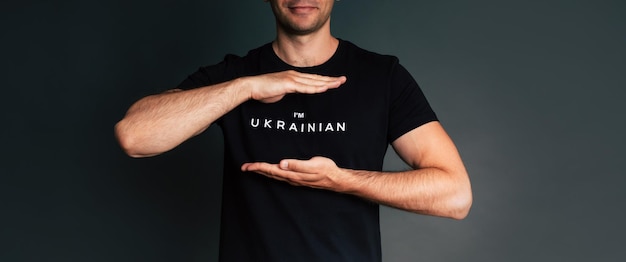 Close up studio photo of young man from Ukraine in black tshirt with sign or slogan i'm ukrainian War in Ukraine Help and support Strong nation Battle for justice freedom and democracy