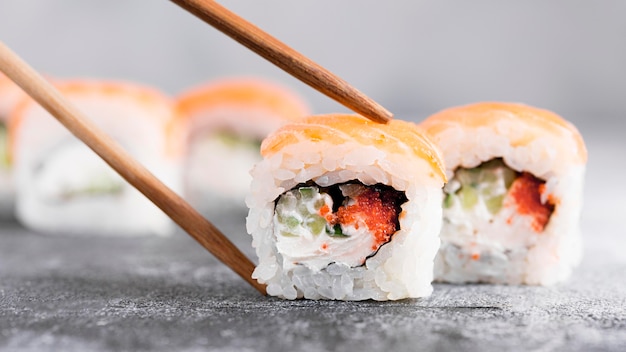 Close-up sushi rolls with chopsticks