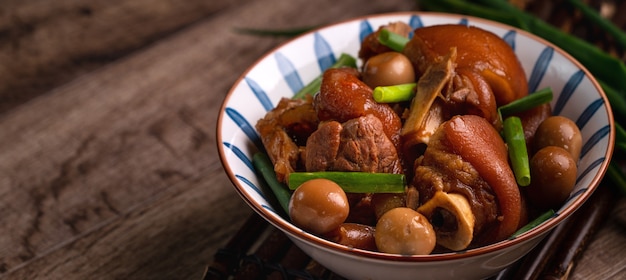 Close up of Taiwanese traditional food pork knuckle in a bowl on rustic table background.