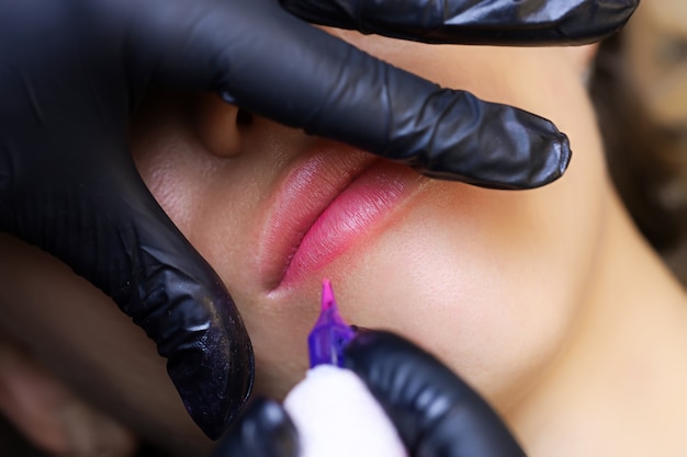 Close-up tattoo with red pigment is performed by machine technology