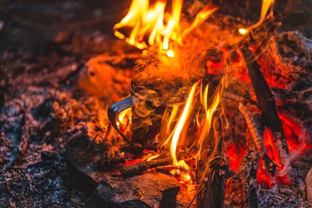 Close up of tea in metal mug heats up in bonfire