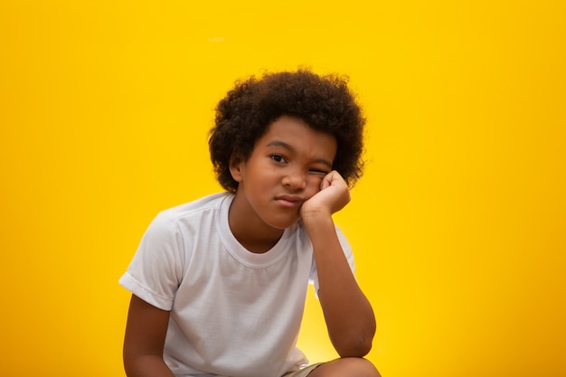 Close up ten year old boy looking to the right with bored facial expression, Isolated on yellow 