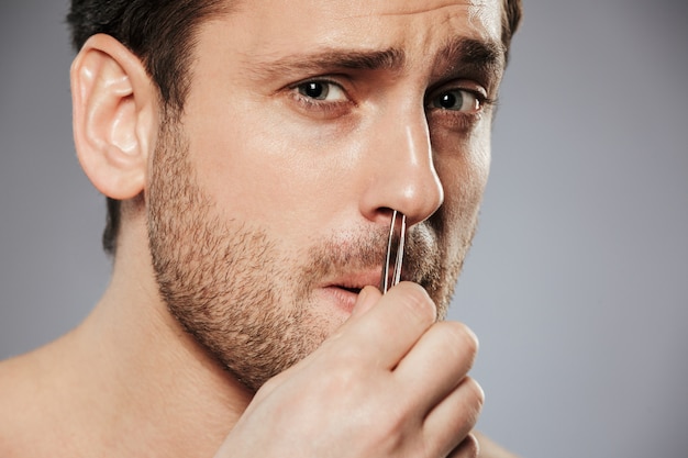 Close up of terrifoed man removing nose hair