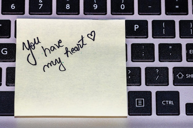 Photo close-up of text on adhesive note over laptop