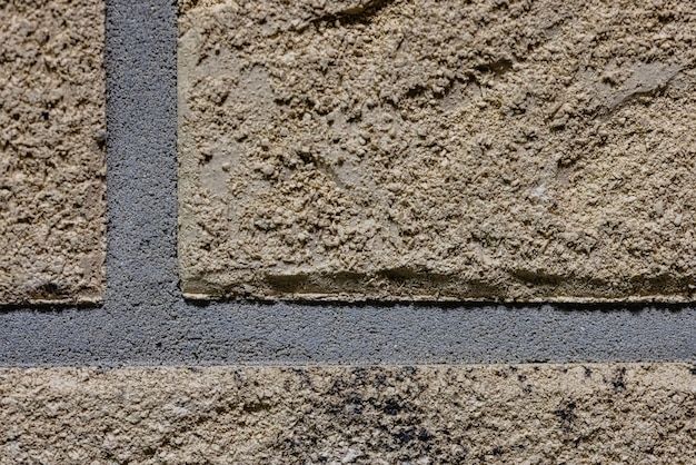 Close-up texture of a brown scratched brick wall with a gray seam