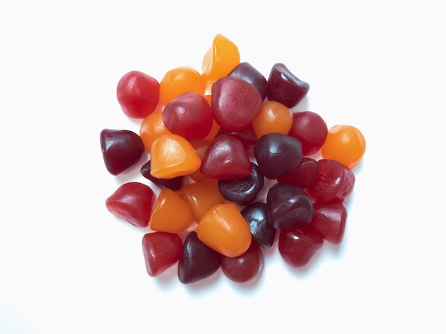 Close-up texture of red, orange and purple multivitamin gummies on white background. Healthy lifestyle concept.