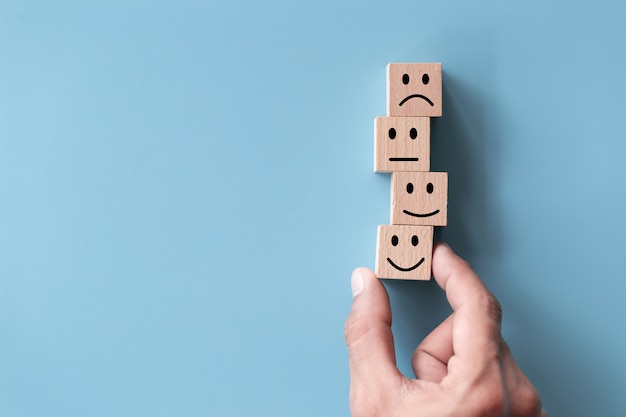 Close up top view customer hand choose smiley face on wood cube