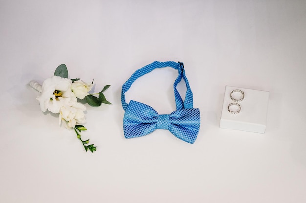 Close up top view of elegant stylish blue male bowtie flowers and two golden rings isolated Preparation for wedding day concept