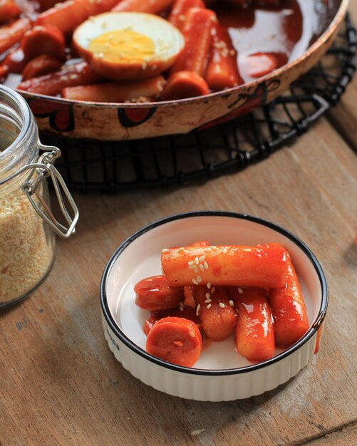 Close Up Topokki or Tteokbokki is Stir-fried Rice Cake with Vegetables and Fish Cake in Spicy Sauce Top with Sesame Seed, Famous and Popular Korean Street Food