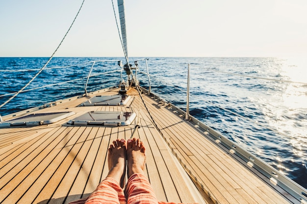 Close up of tourist woman caucasian feet lay down and relaxing enjoying a sail boat trip with ocean around and horizon  