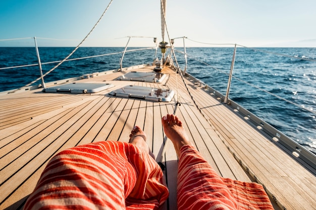 Close up of tourist woman caucasian feet lay down and relaxing enjoying a sail boat trip with ocean around and horizon  