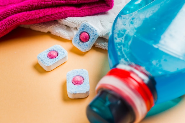 Close-up of towels and liquid detergent with three dishwasher tablets