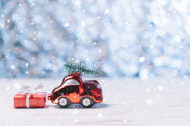 Close-up toy car carries a Christmas tree and a box with a gift, concept Christmas and New Year