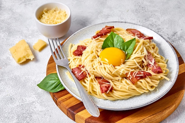 Close up Traditional Italian Pasta Carbonara with bacon, cheese and egg yolk on plate on light background.