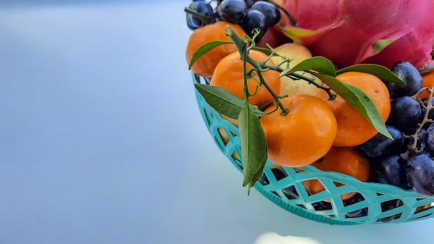 Close up, Tropical Dragon Fruit Oranges, pears, grapes in a green Basket on a white background 01