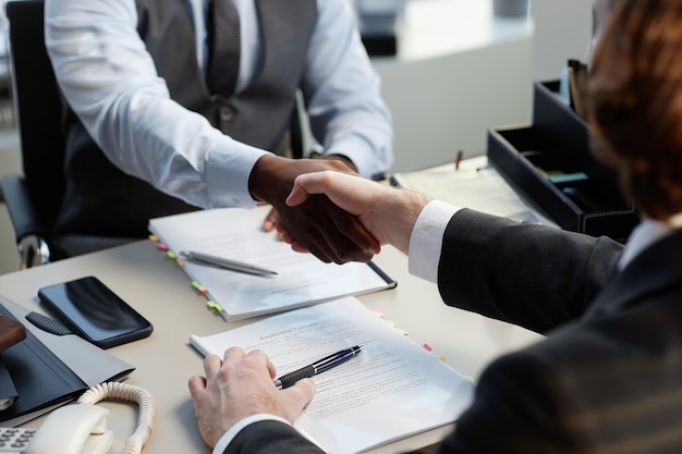 Close up of two business partners shaking hands over table