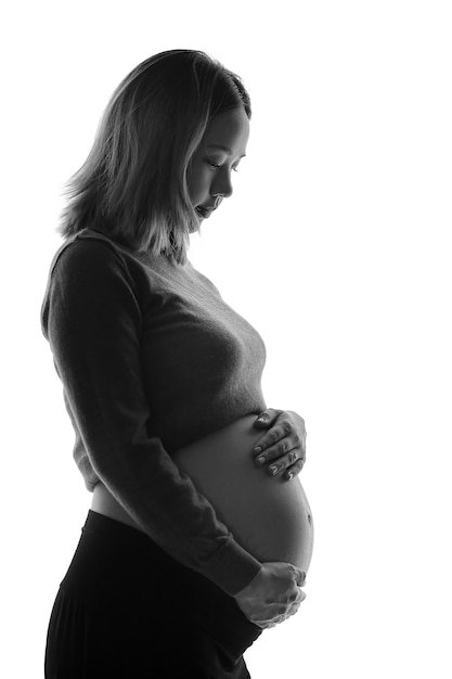 Close up of two hands wearing wedding rings on pregnant woman touching her big belly