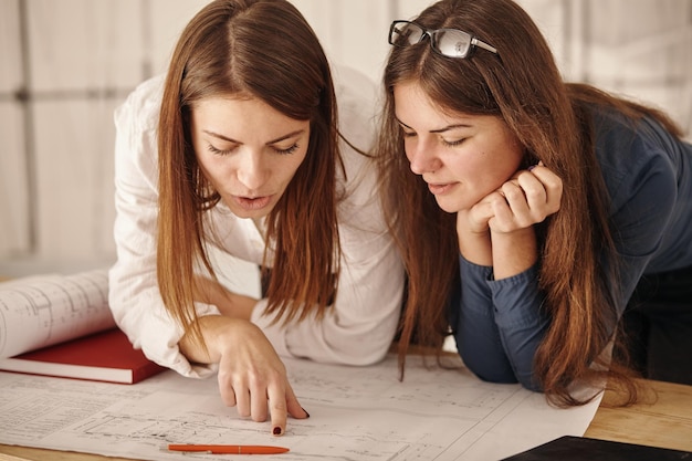 Close up Two Happy Young Businesswomen at the Office Talking About Business Report on Paper.