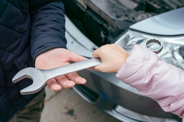 Close up of two mechanics sharing metal spanner