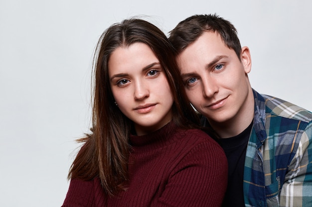 A close up of two people in love standing close to each other. A handsome boy with charming blue eyes dressed