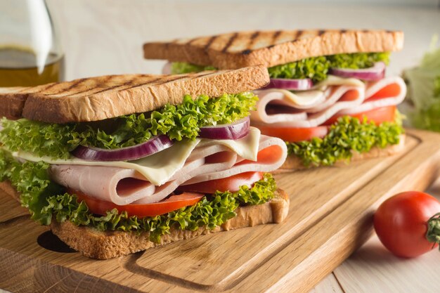 Close up of two sandwiches with bacon, salami, prosciutto and fresh vegetables