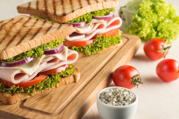 Close up of two sandwiches with bacon, salami, prosciutto and fresh vegetables