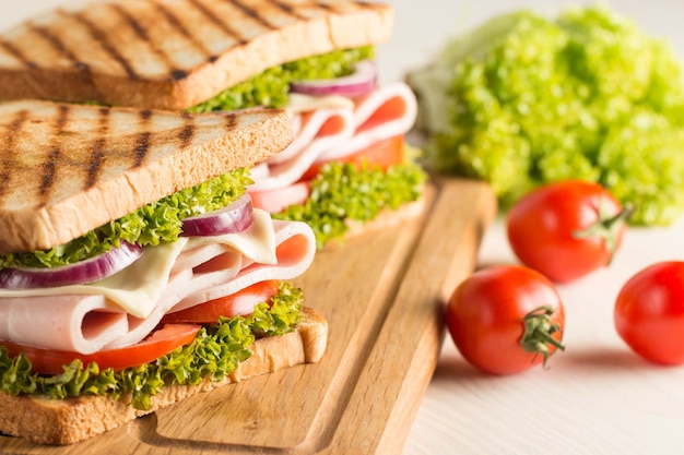 Close up of two sandwiches with bacon, salami, prosciutto and fresh vegetables