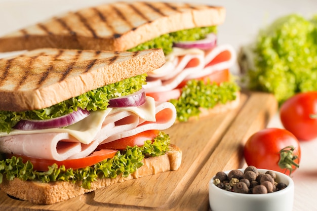 Close up of two sandwiches with bacon, salami, prosciutto and fresh vegetables