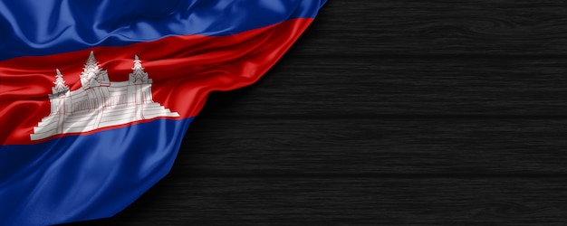 Close up of united states of Cambodia flag on the black wooden background 3d render