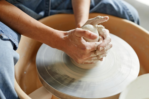 Close up of unrecognizable artist shaping clay on pottery wheel, copy space