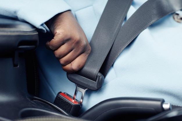 Close up of unrecognizable black woman fasting safety belt in car copy space