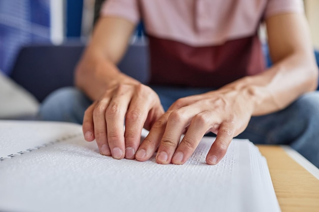 Close up of unrecognizable blind man reading book in tactile braille focus on hands touching page co