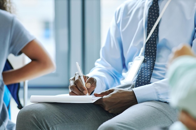 Close up of unrecognizable male therapist taking notes during session with support group copy space