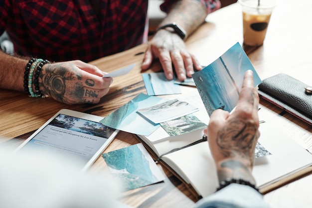 Close-up of unrecognizable men watching beautiful nature photos from travel while planning new journey