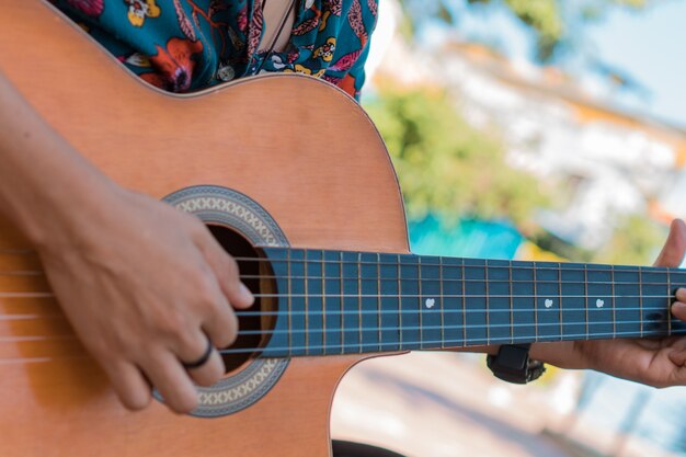 Close-up of an unrecognizable woman playing acoustic guitar in the park