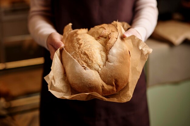 Photo close up of unrecognizable young woman carefully holding fresh bread in artisan bakery copy space