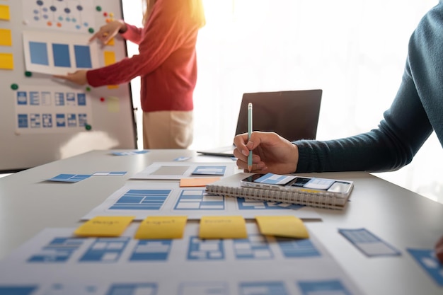 Close up ux developer and ui designer brainstorming about mobile app interface wireframe design at modern office Creative digital development agency