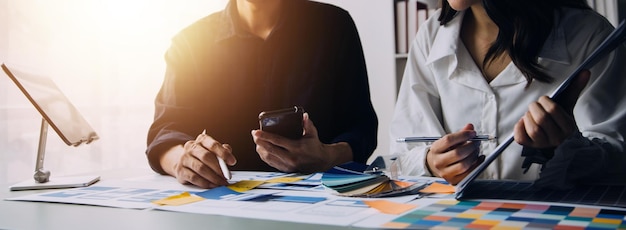 Close up ux developer and ui designer brainstorming about mobile app interface wireframe design on table with customer breif and color code at modern officeCreative digital development agency