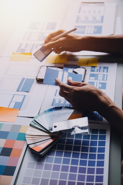 Close up ux developer and ui designer brainstorming about mobile app interface wireframe design on table with customer breif and color code at modern officeCreative digital development agency