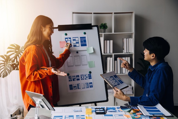 Close up ux developer and ui designer brainstorming about mobile app interface wireframe design on table with customer breif and color code at modern officeCreative digital development agency